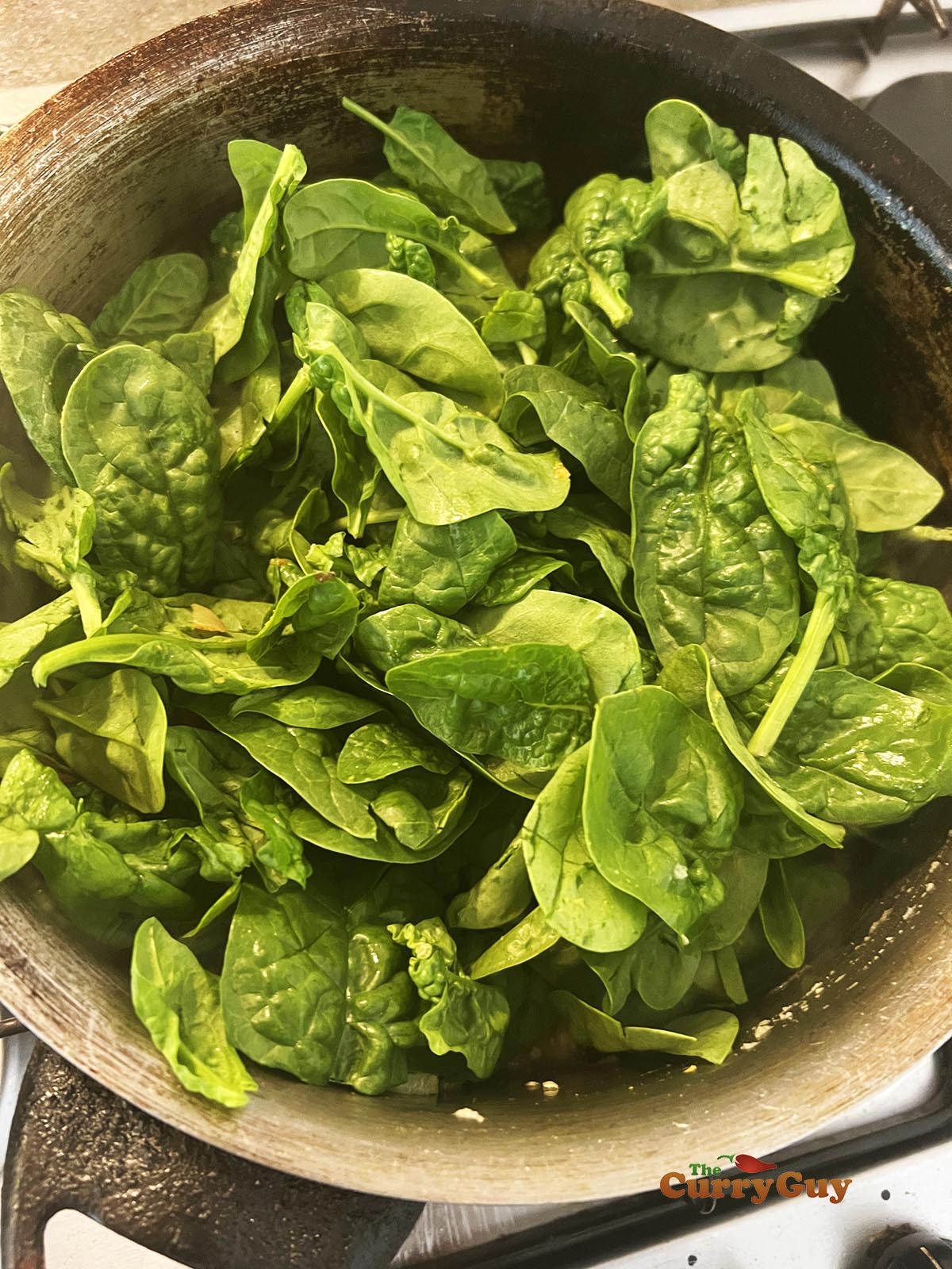 Adding spinach leaves to the pan