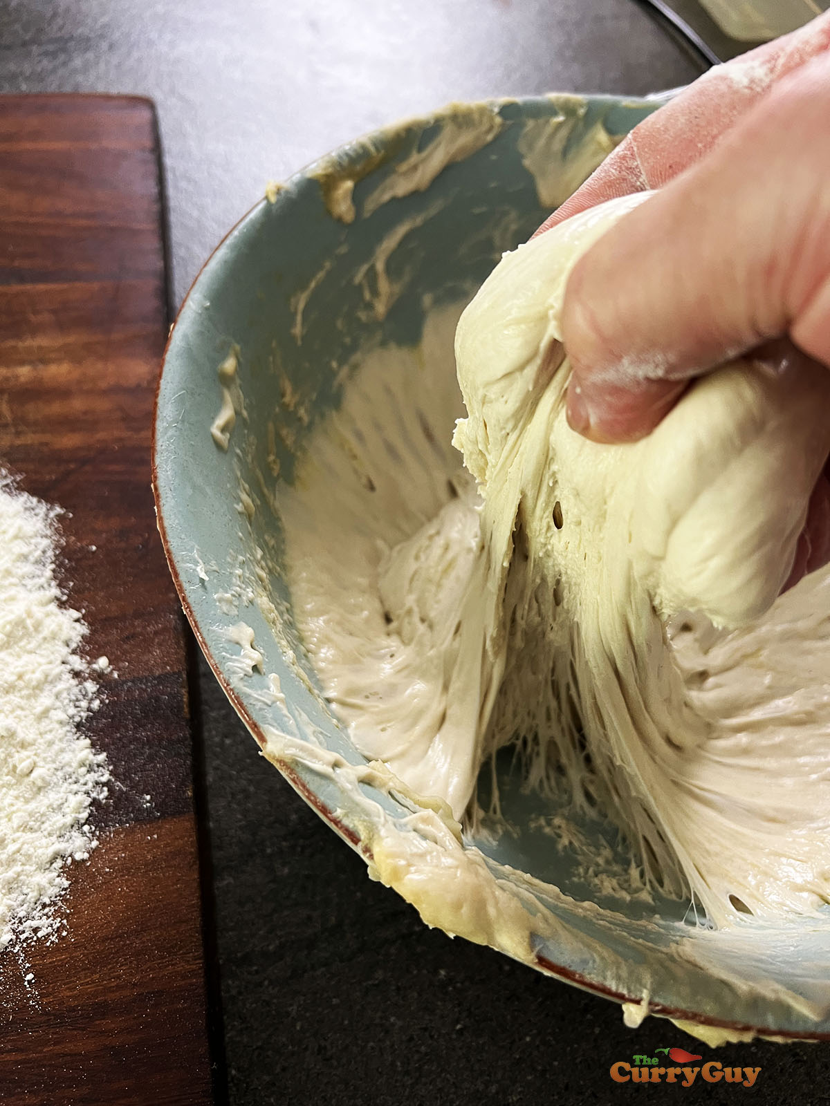 Grabbing dough to form into a pita.