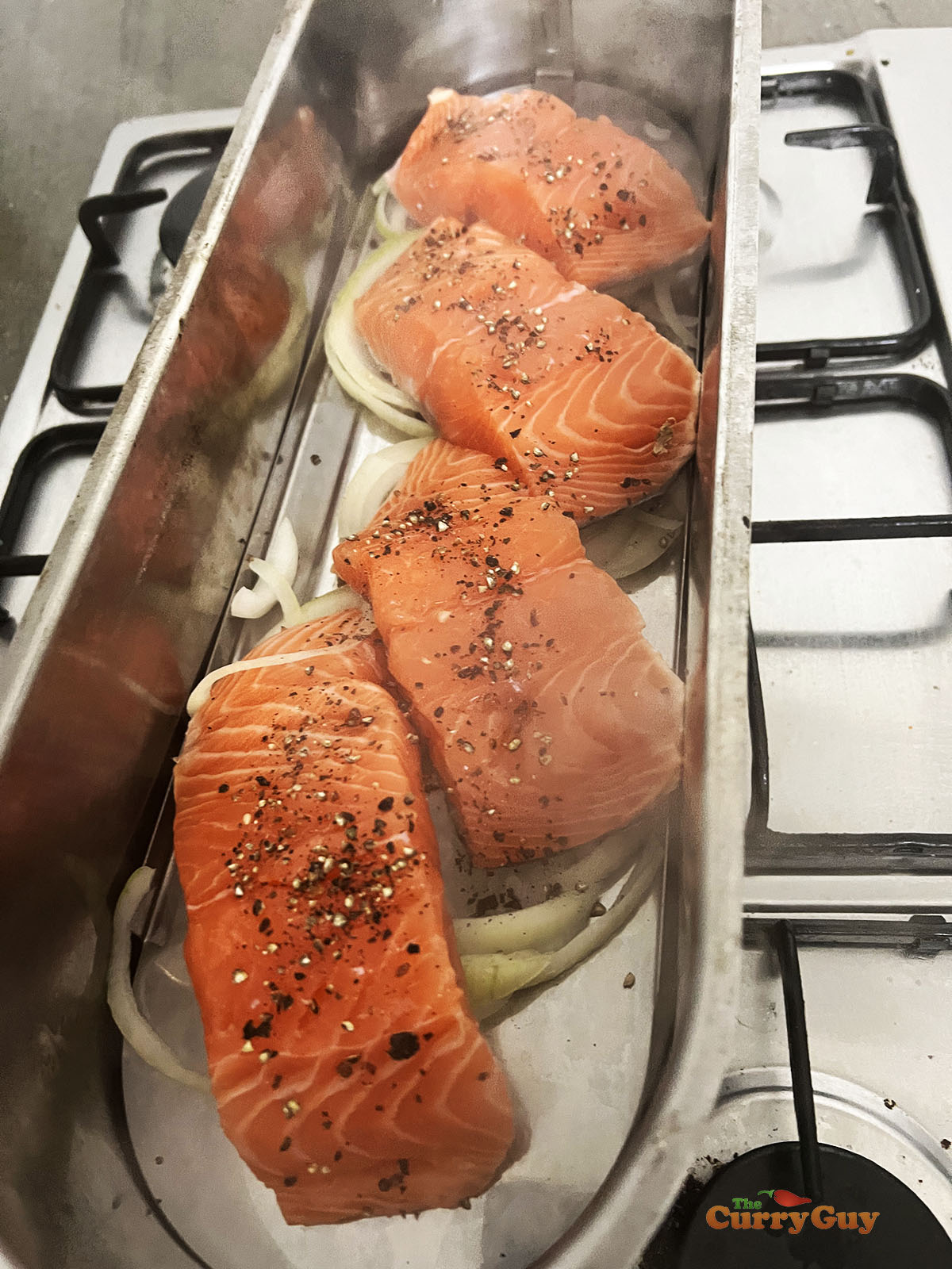 Salmon resting on sliced onions in a steamer.