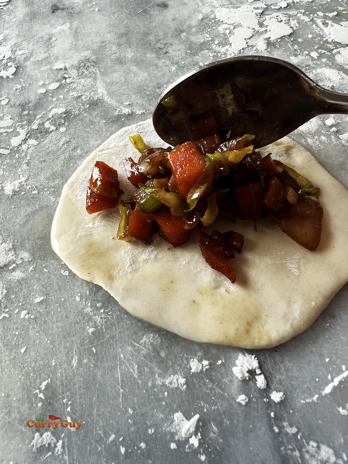 Putting a spoonful of the vegetable filling on a momo wrapper.