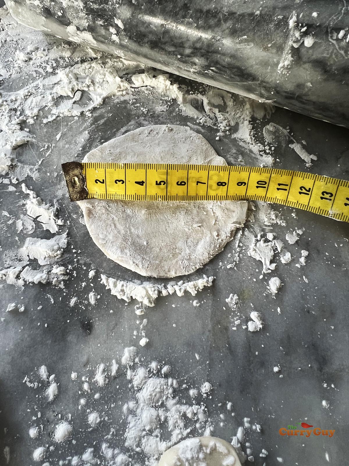 Rolling out the dough to form wrappers for the momos. There is a ruler showing that the momo round is 9cm in diameter.