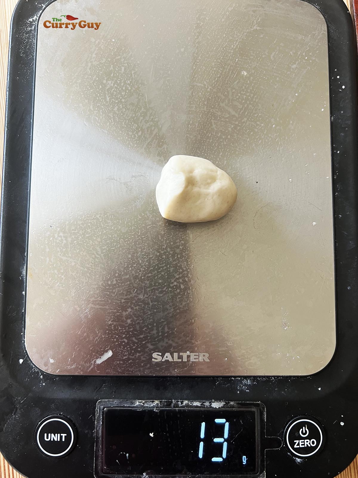 Weighing the dough pieces to make equal sized momos.