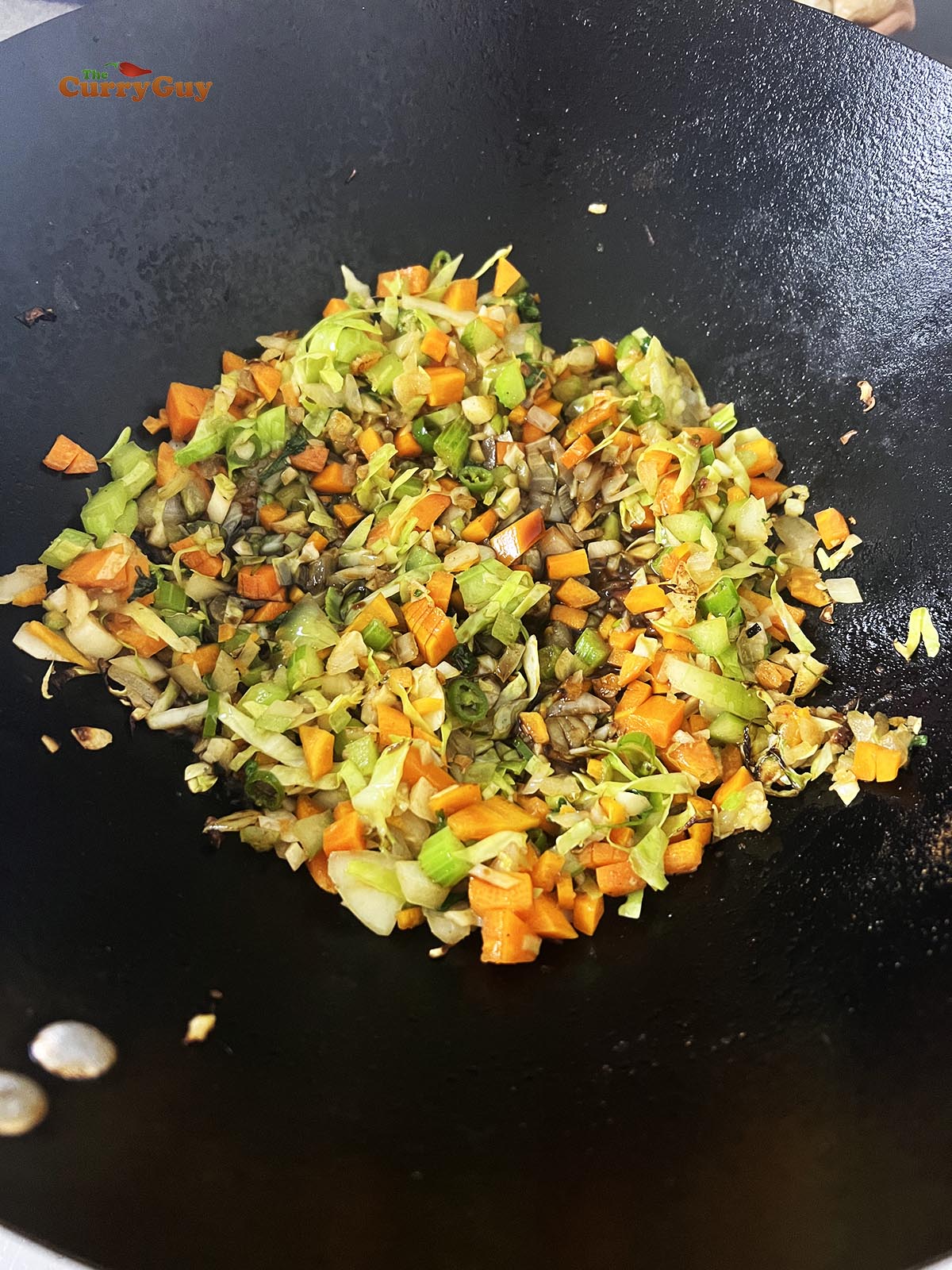 Adding soy sauce to the vegetable mixture.