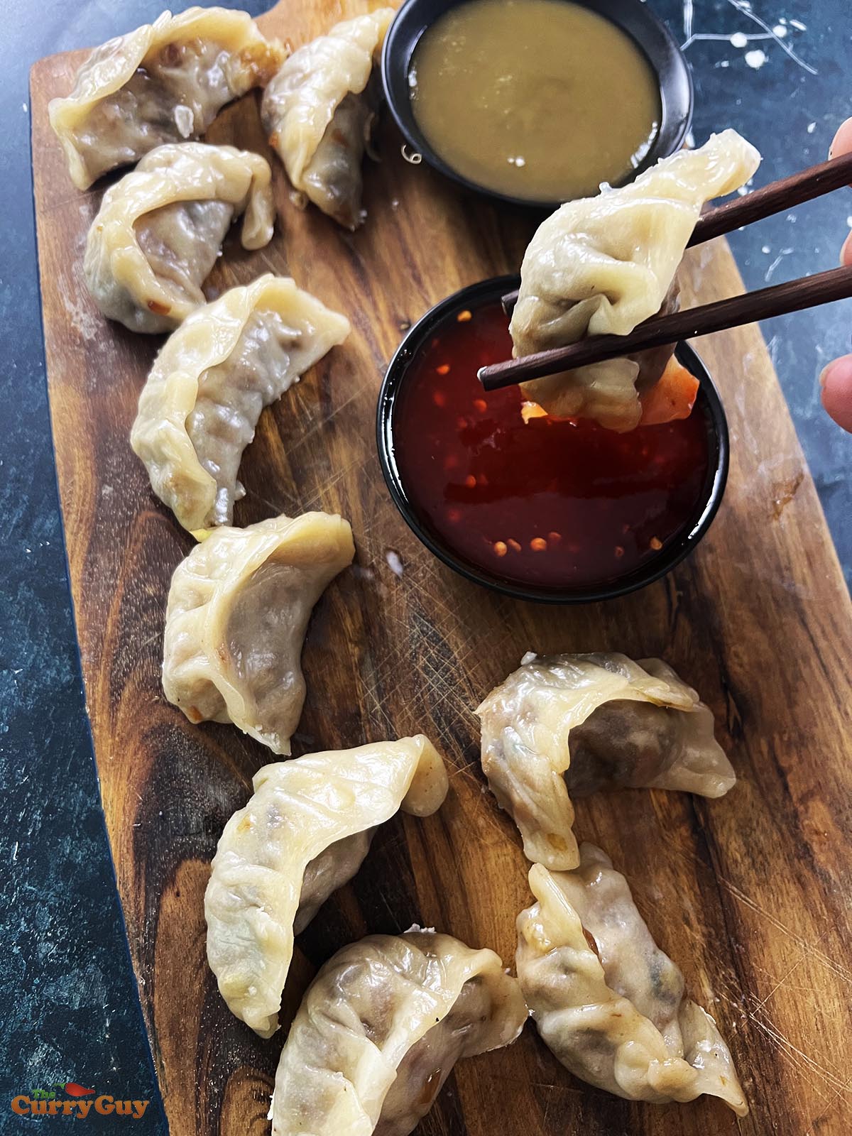 Dipping a vegetable momo in a chili dipping sauce.