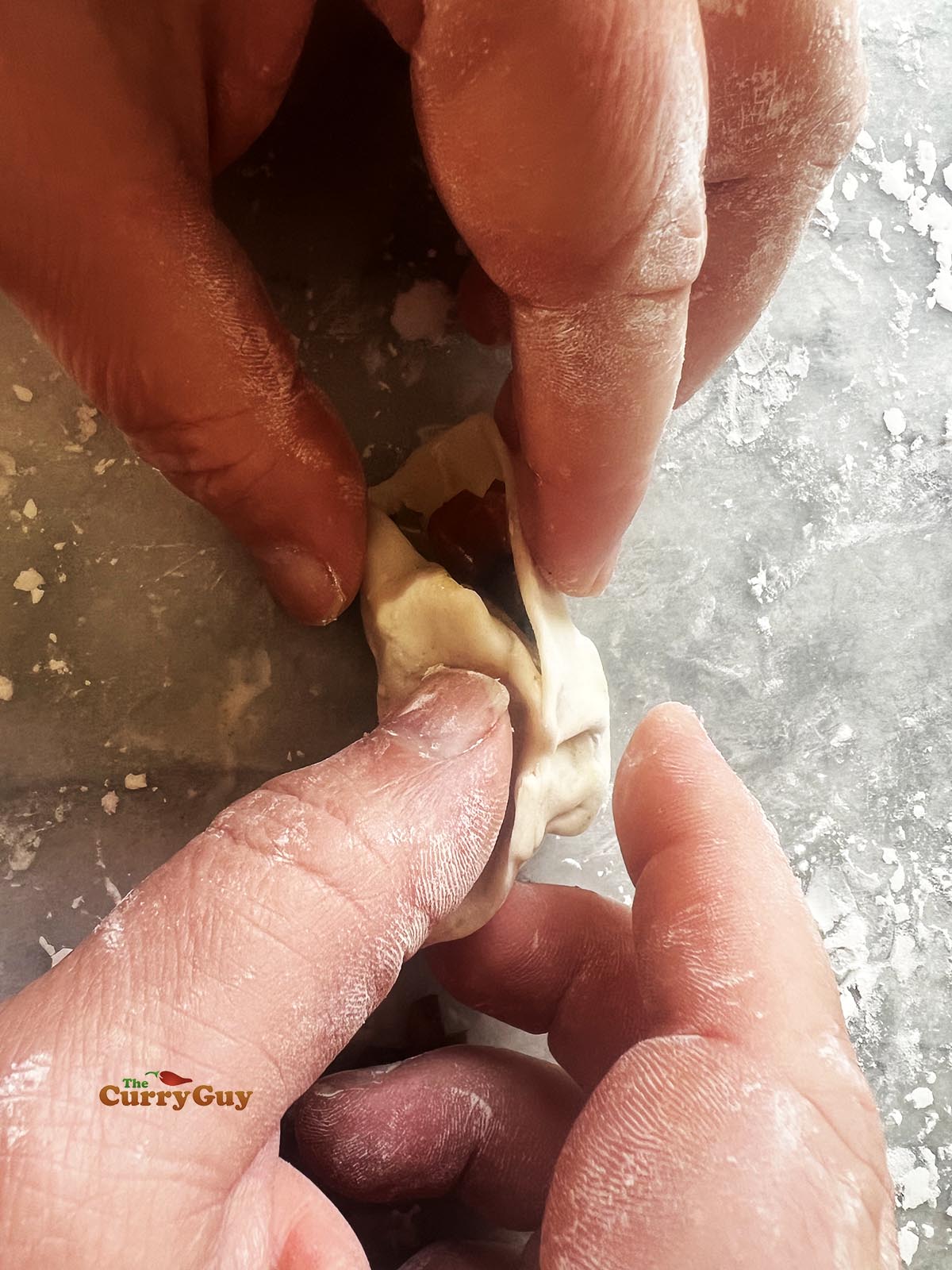 Sealing the momo wrapper closed.