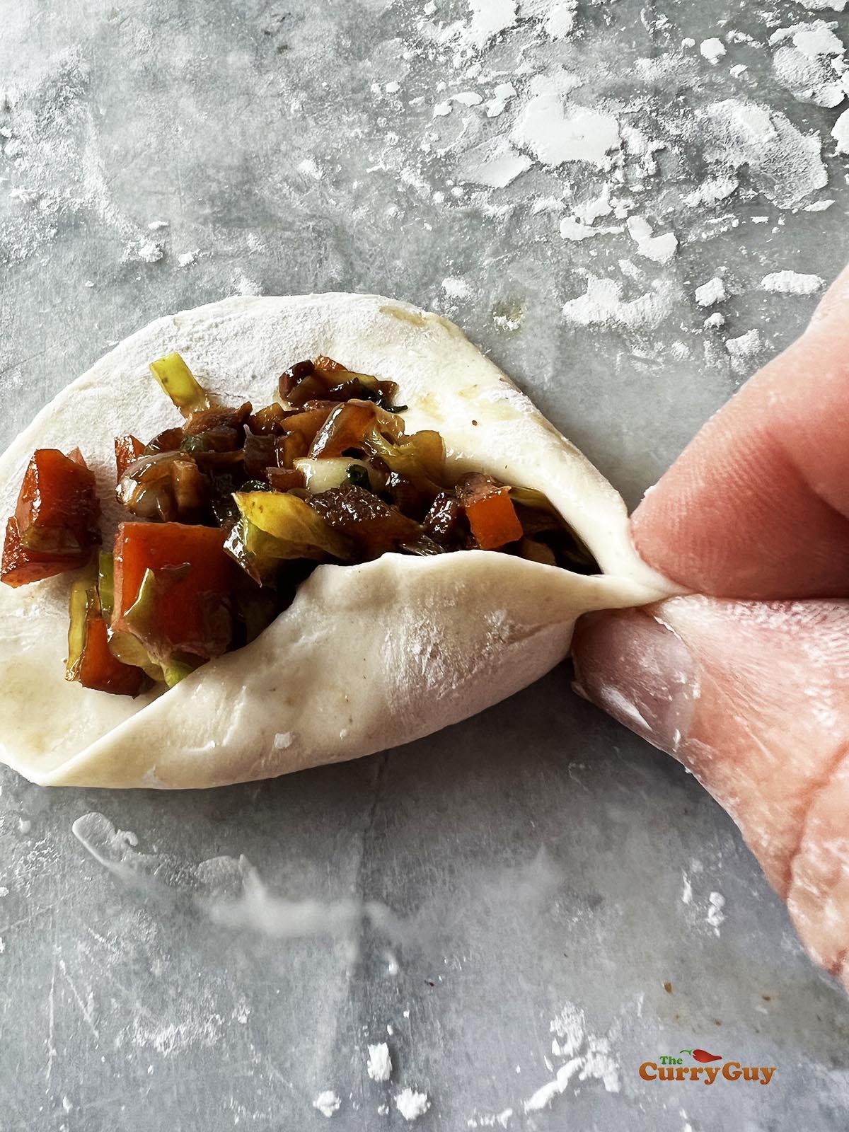 Folding and sealing one end of the momo wrapper.