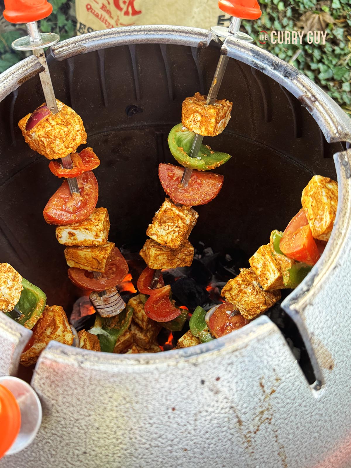 The paneer tikka skewers in a tandoor cooking.
