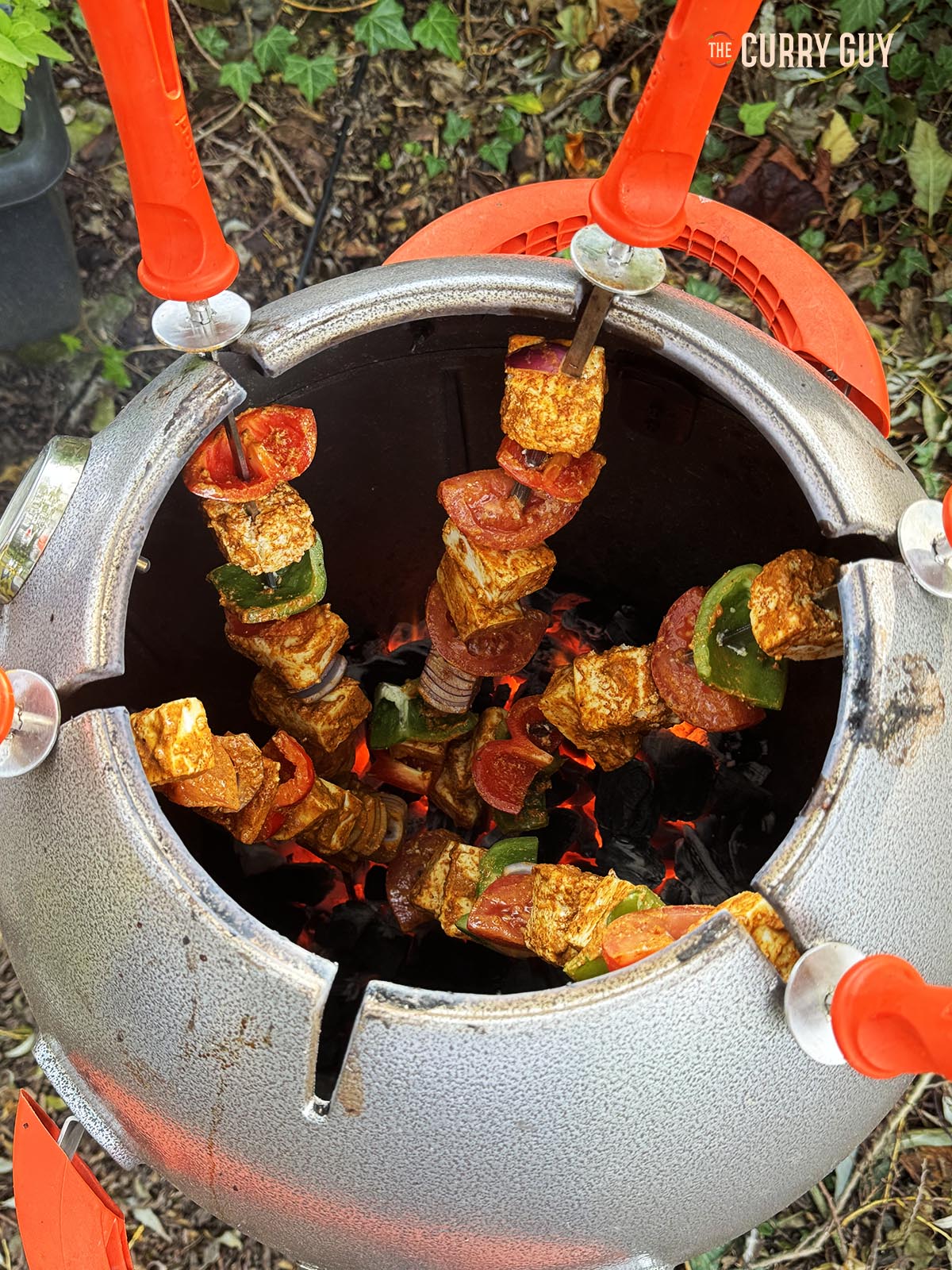 Paneer tikka cooking in a tandoor oven.