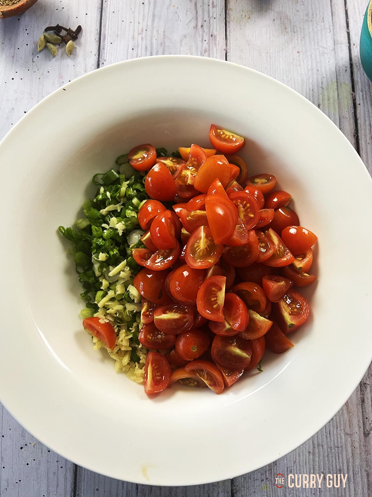 The tomatoes, spring onions (scallions) and chopped ginger in a serving bowl ready for chilling.