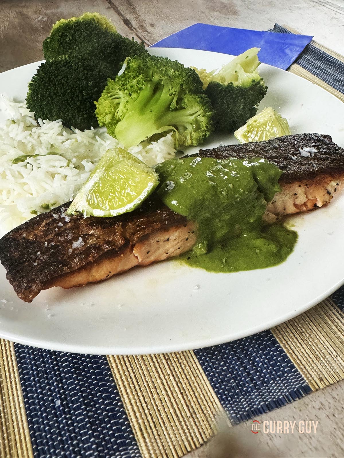 Crispy Skin Salmon garnished with the coriander and cashew sauce on a serving plate with rice and vegetables. 