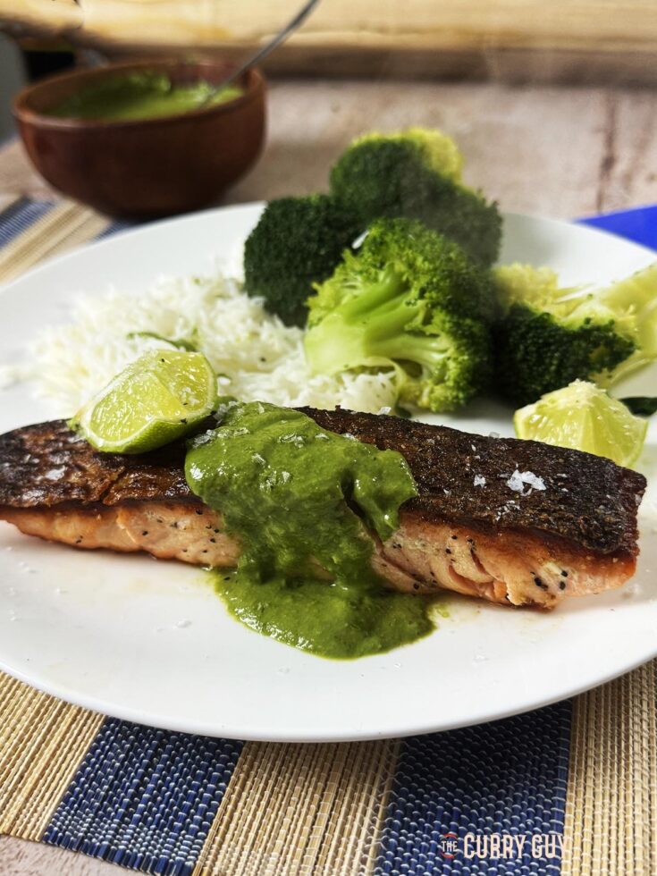 Crispy skin salmon on a serving plate garnished with green coriander and cashew sauce.