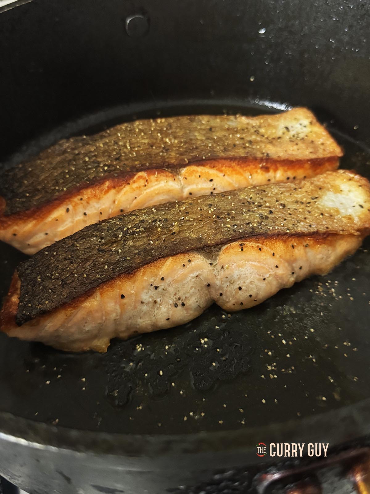 The crispy skin salmon in the pan with the skin side facing up.