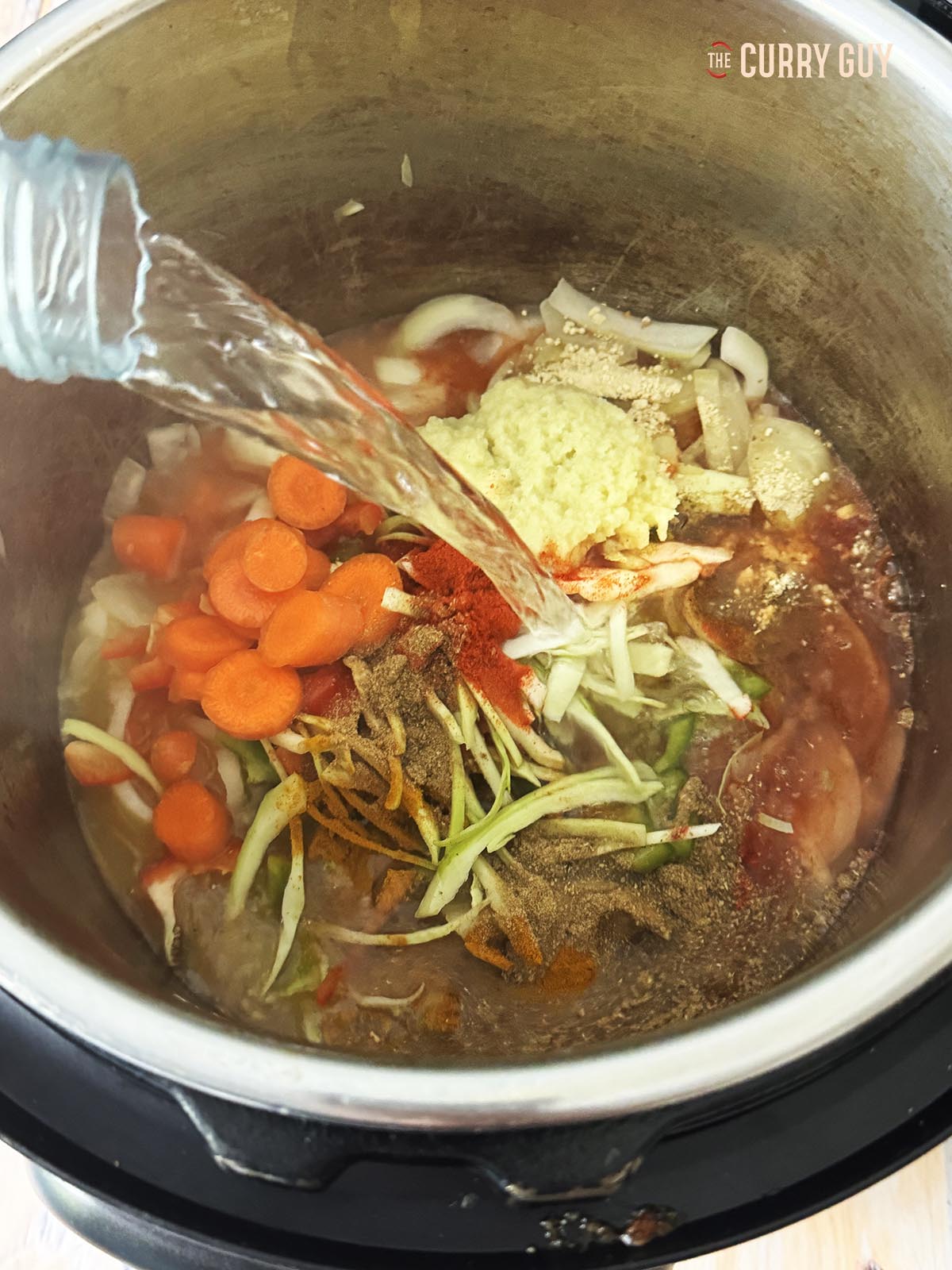 Adding water to the ingredients in the multi cooker.
