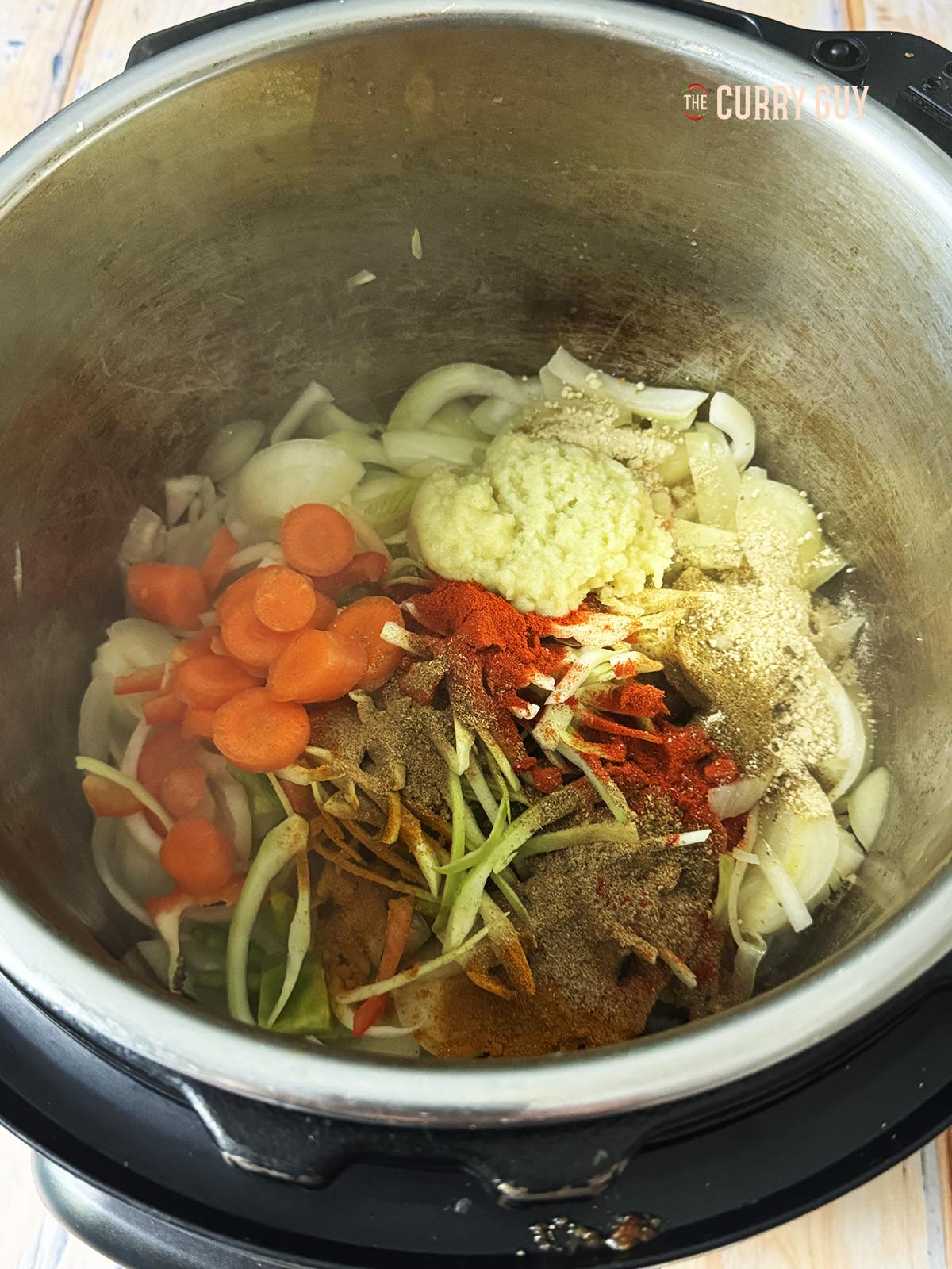 Adding the spices and remaining vegetables to the multi cooker.