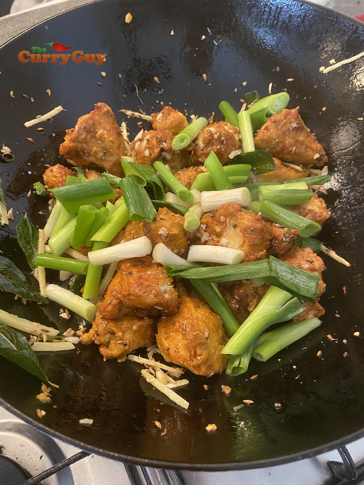 Adding spring onions to pan.