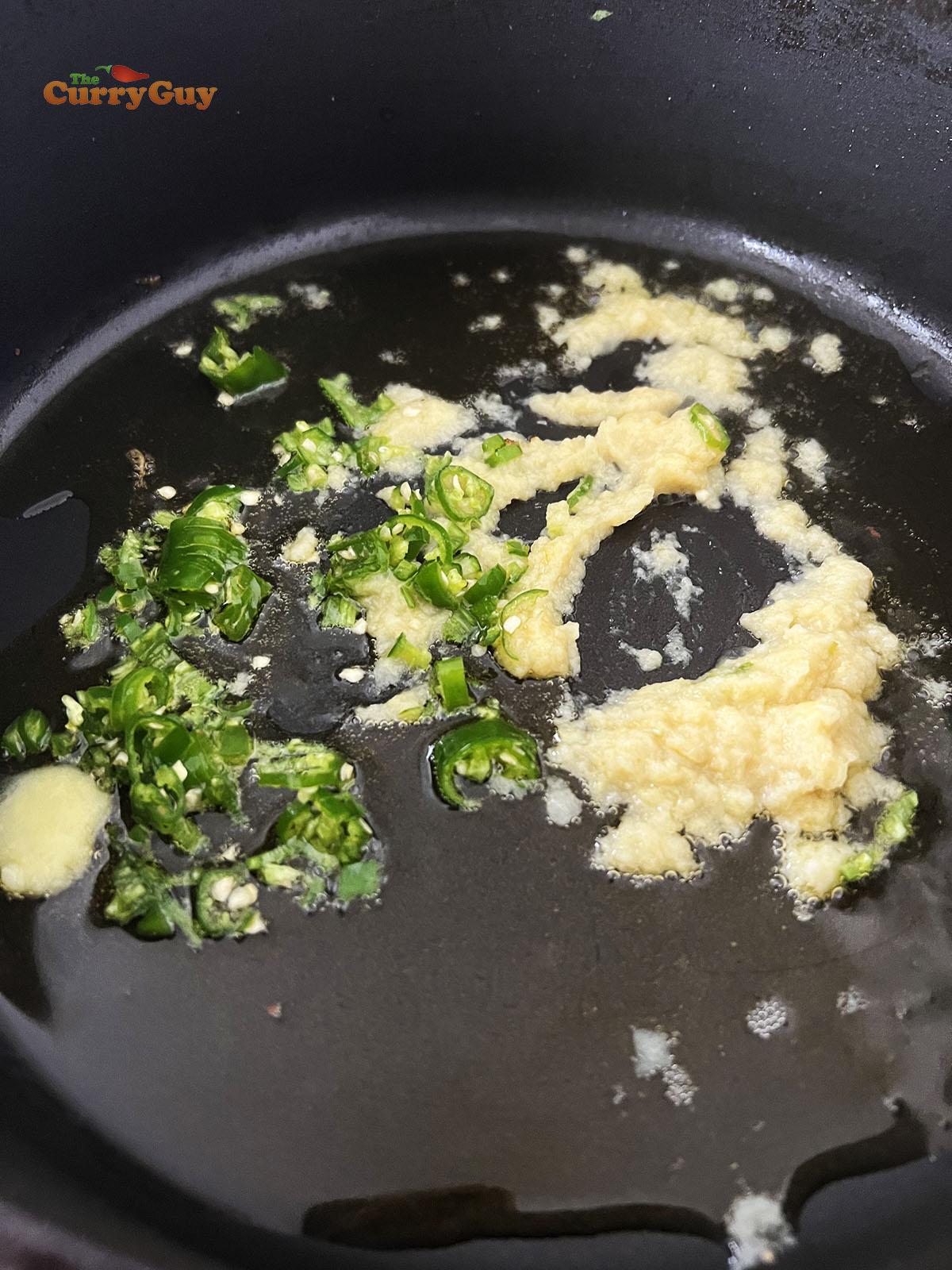 Adding garlic and ginger paste and chopped chillies to melted ghee.