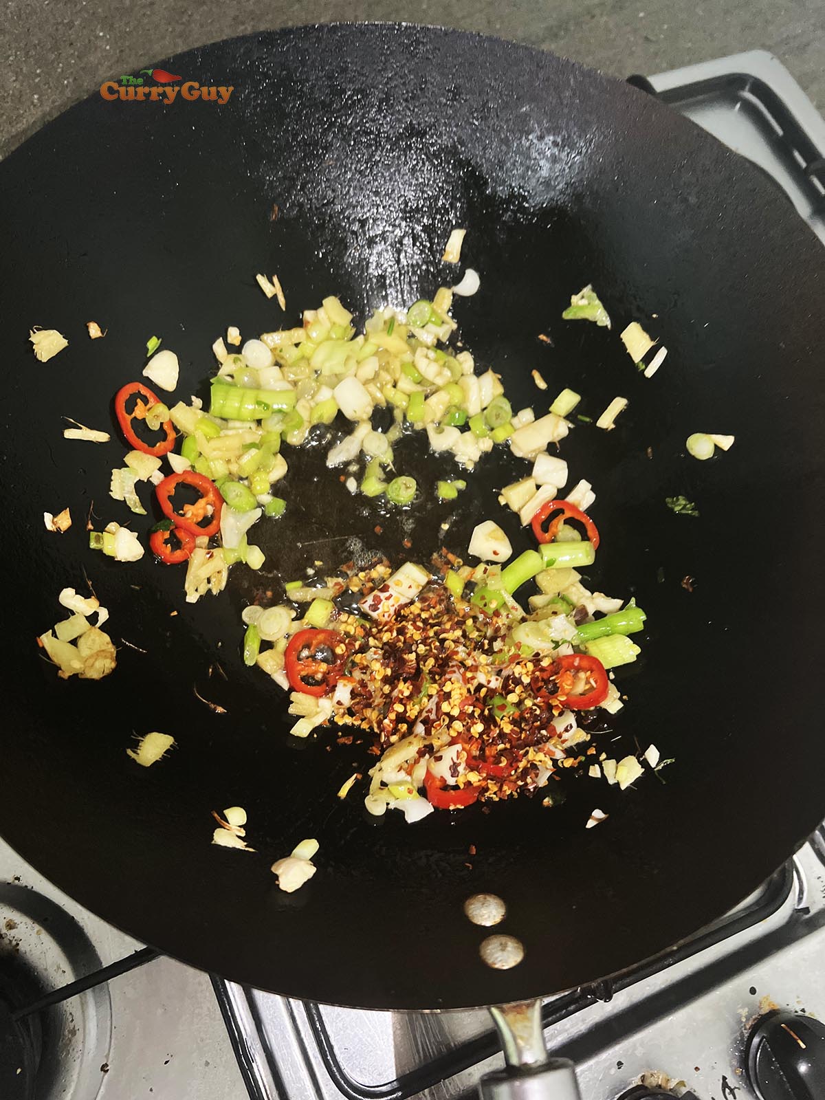 Adding chillies and dried chilli flakes to the wok.