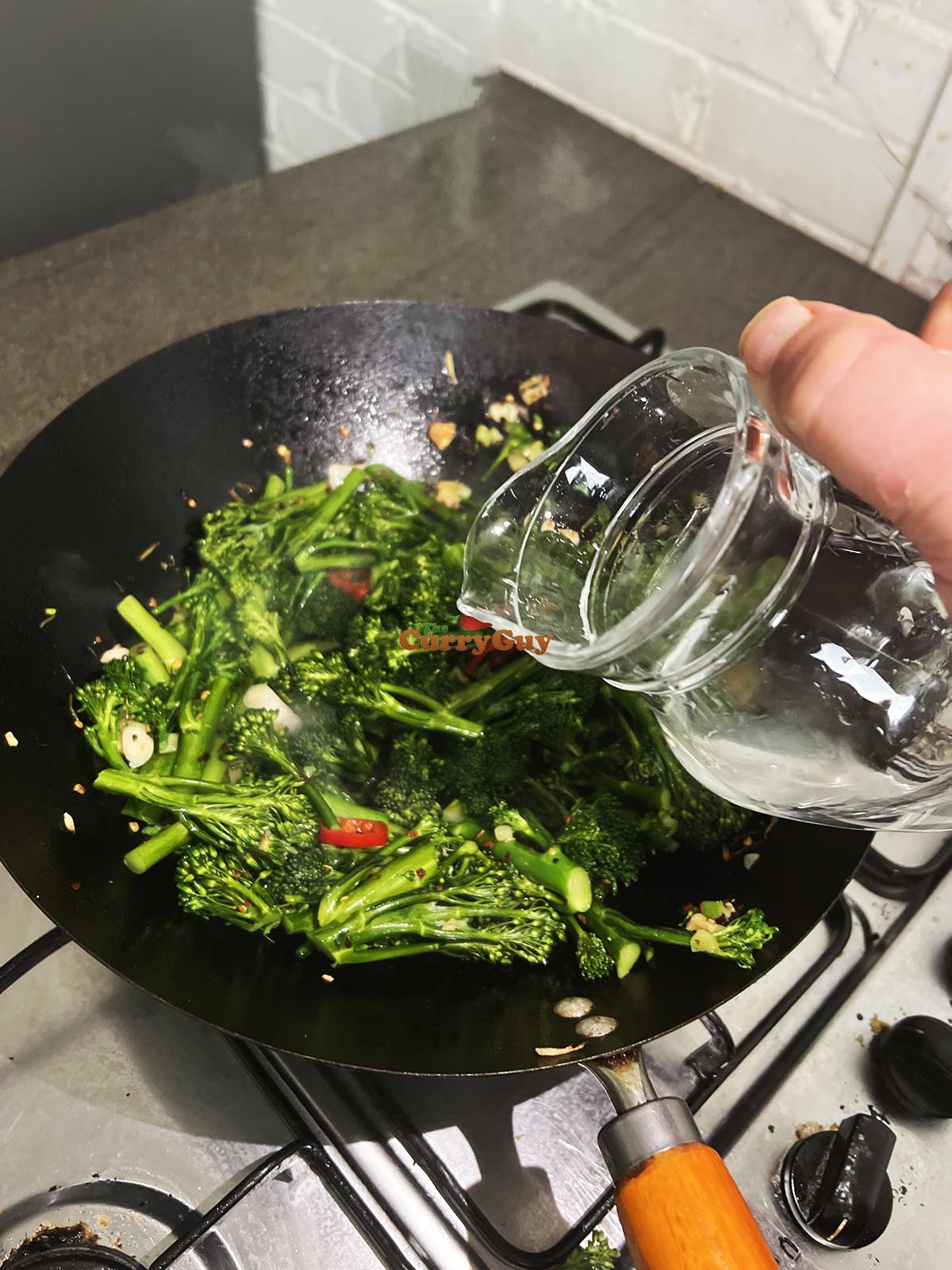 Adding a little water to the wok. 