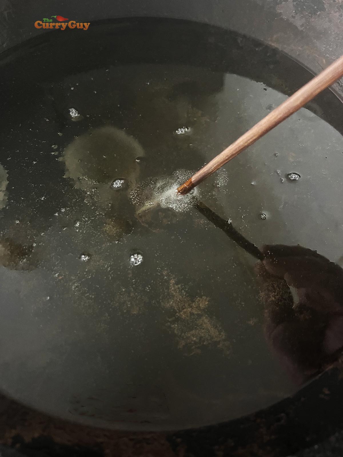 Testing the heat of oil with a wooden chopstick.