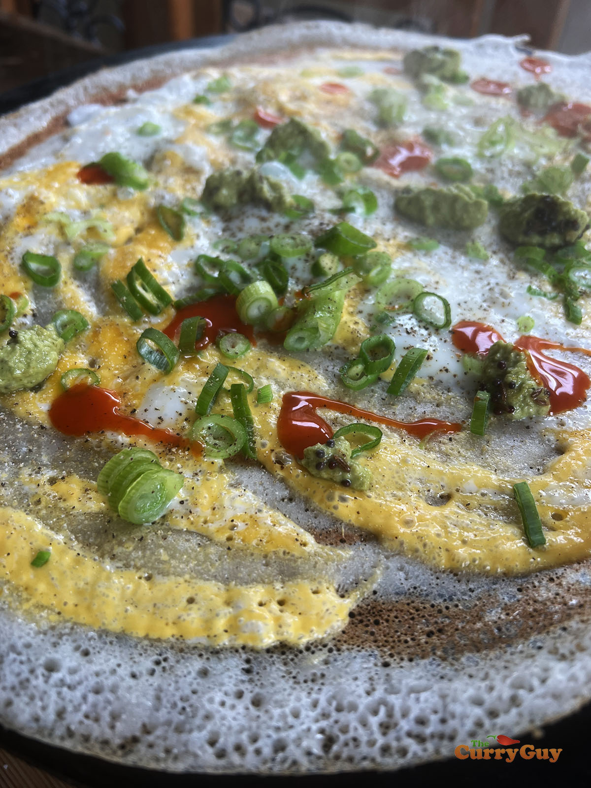 Decorating the egg dosa with spring onions and hot sauce, salt and pepper.