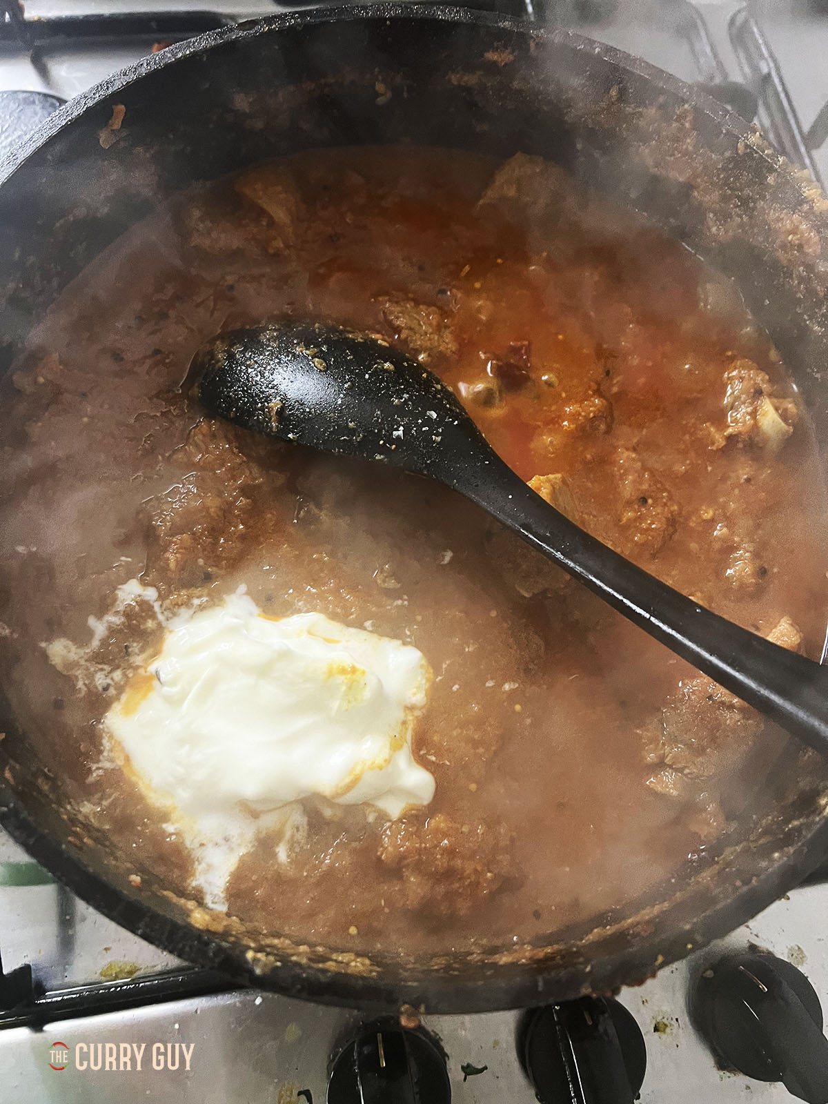 Adding yoghurt to the pan.