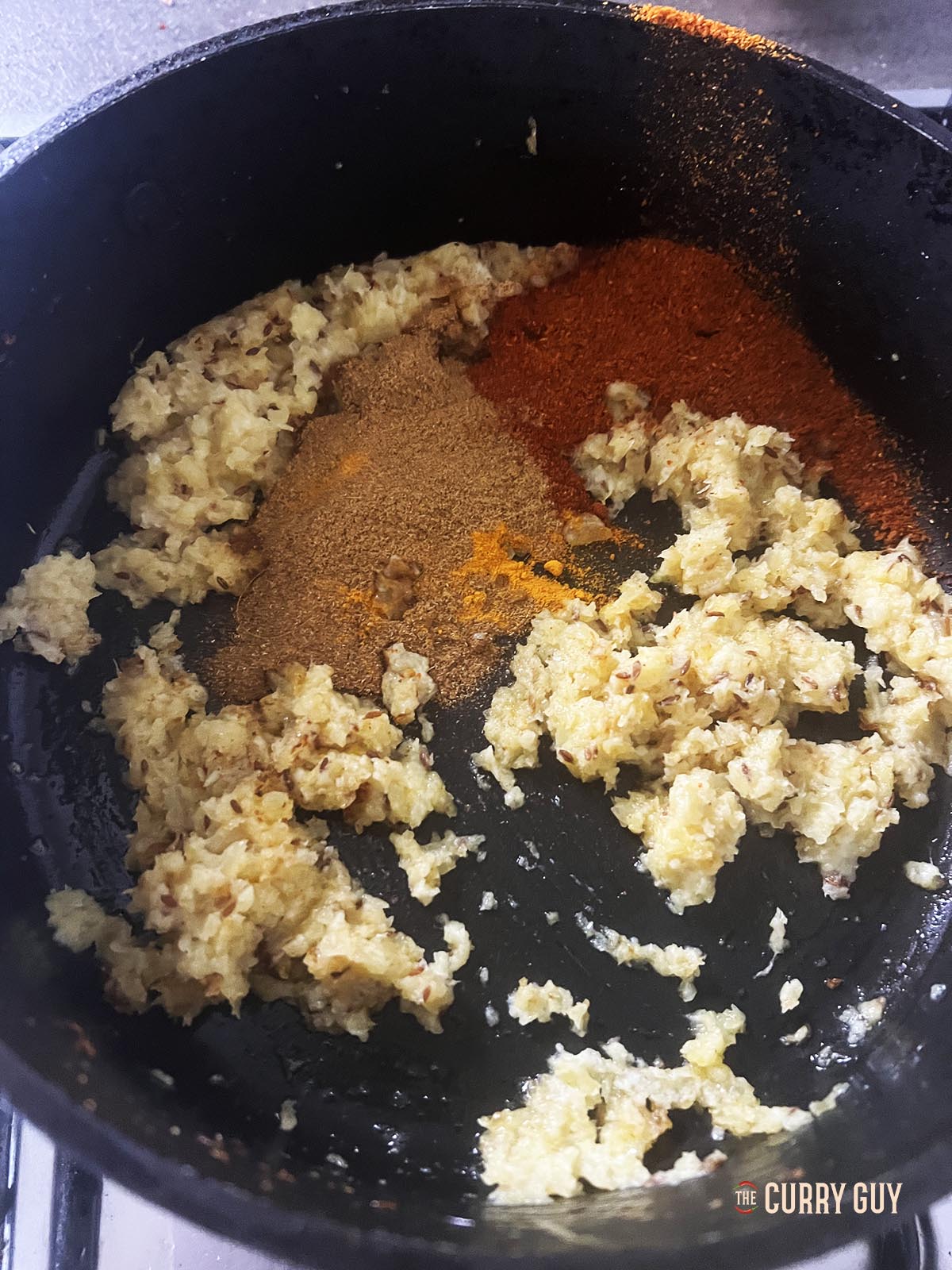 Adding the ground spices to the pan.