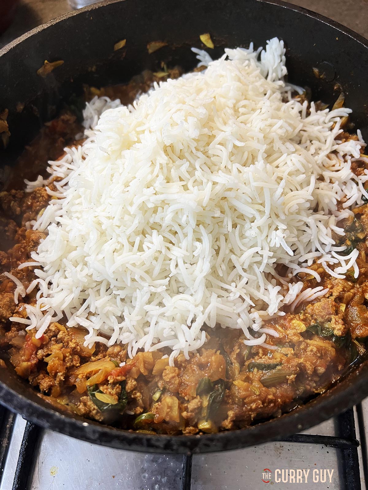 Adding the cold rice to the biryani.