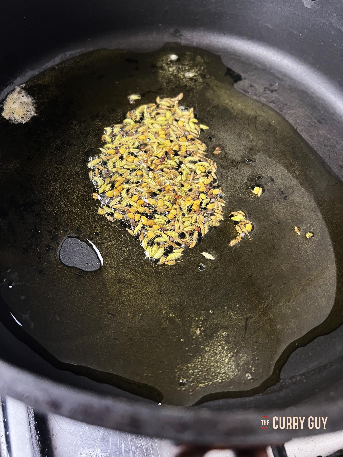 Adding panch poran to the oil in the pan.