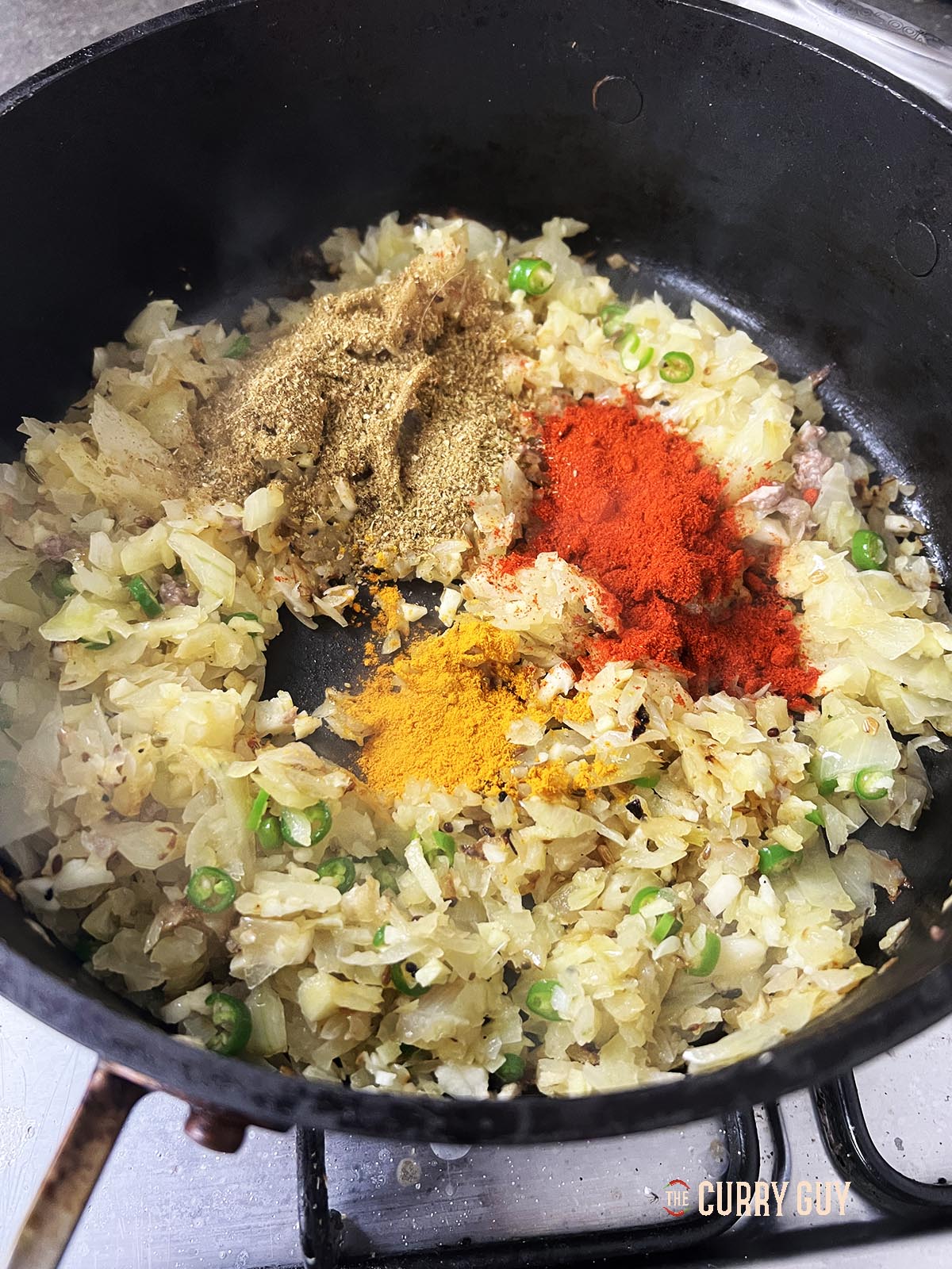 Adding ground spices to the pan.