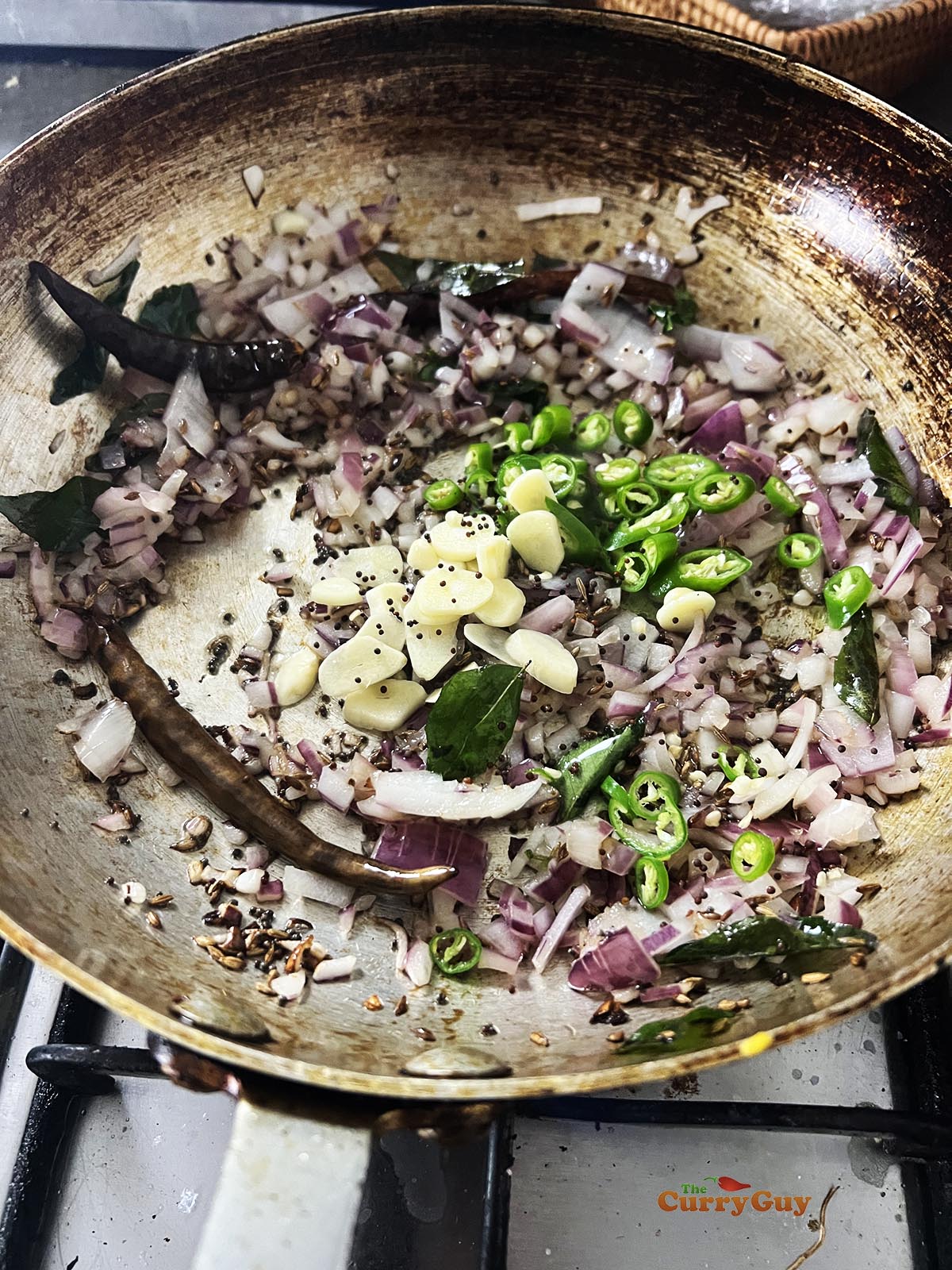 Adding onions, chilies and garlic to the ghee.