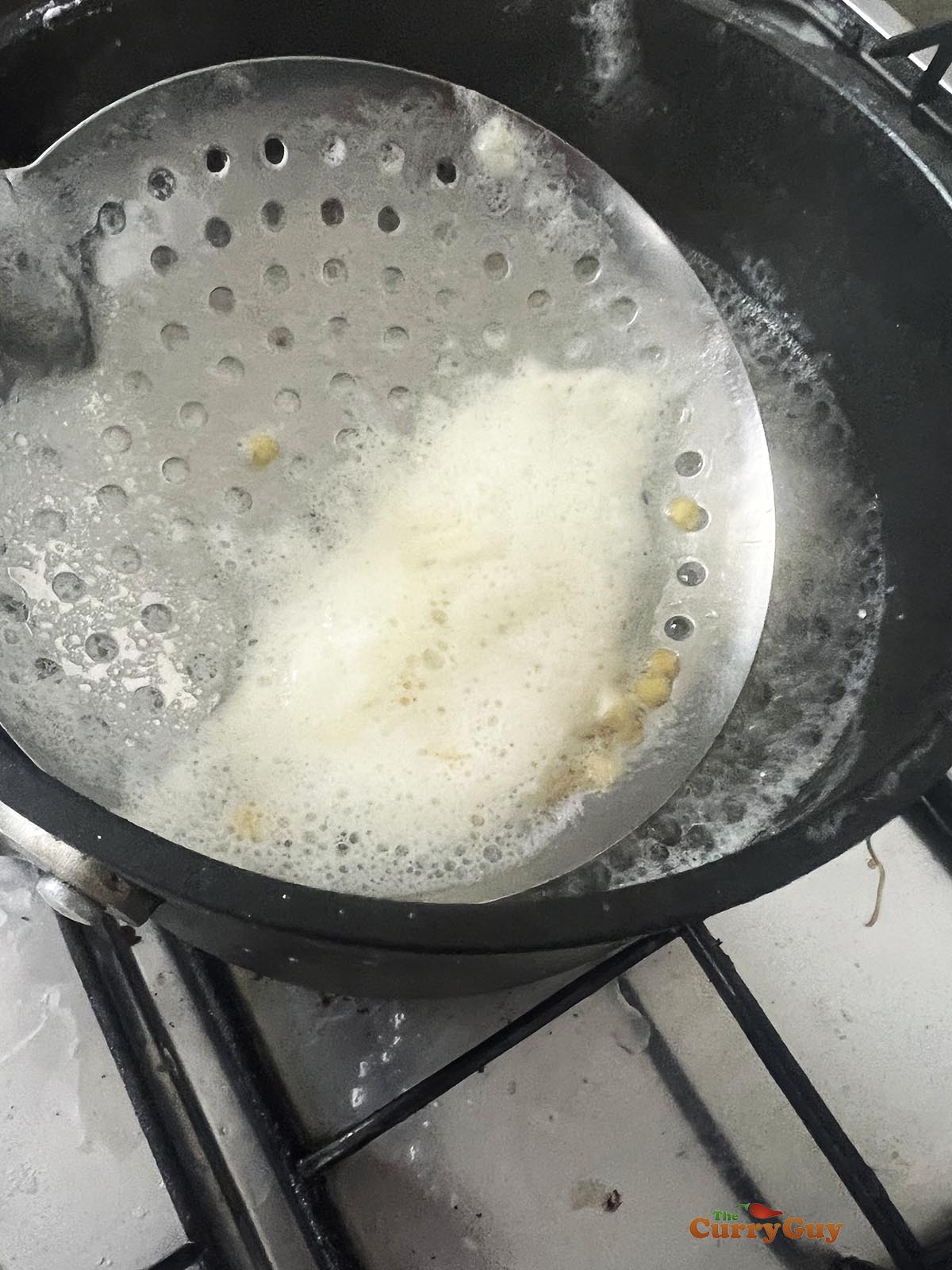 Slimming the foam off the simmering lentils