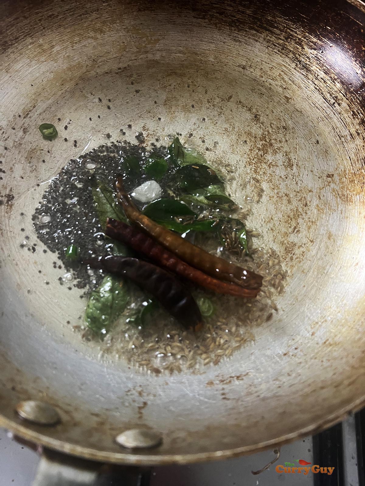 Preparing the tarka. Infusing mustard seeds, cumin, cinnamon, cardamom and curry leaves into hot ghee.