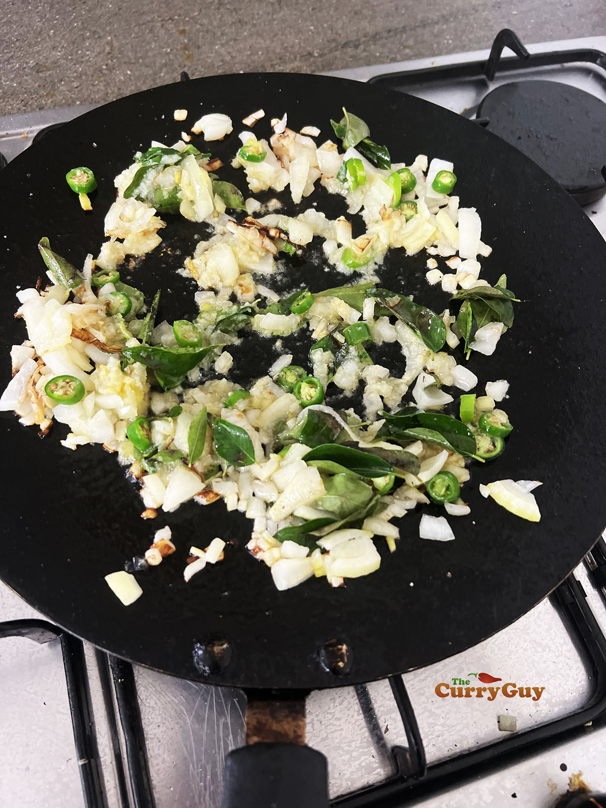 Frying onions, garlic, ginger, chillies and curry leaves in the pan