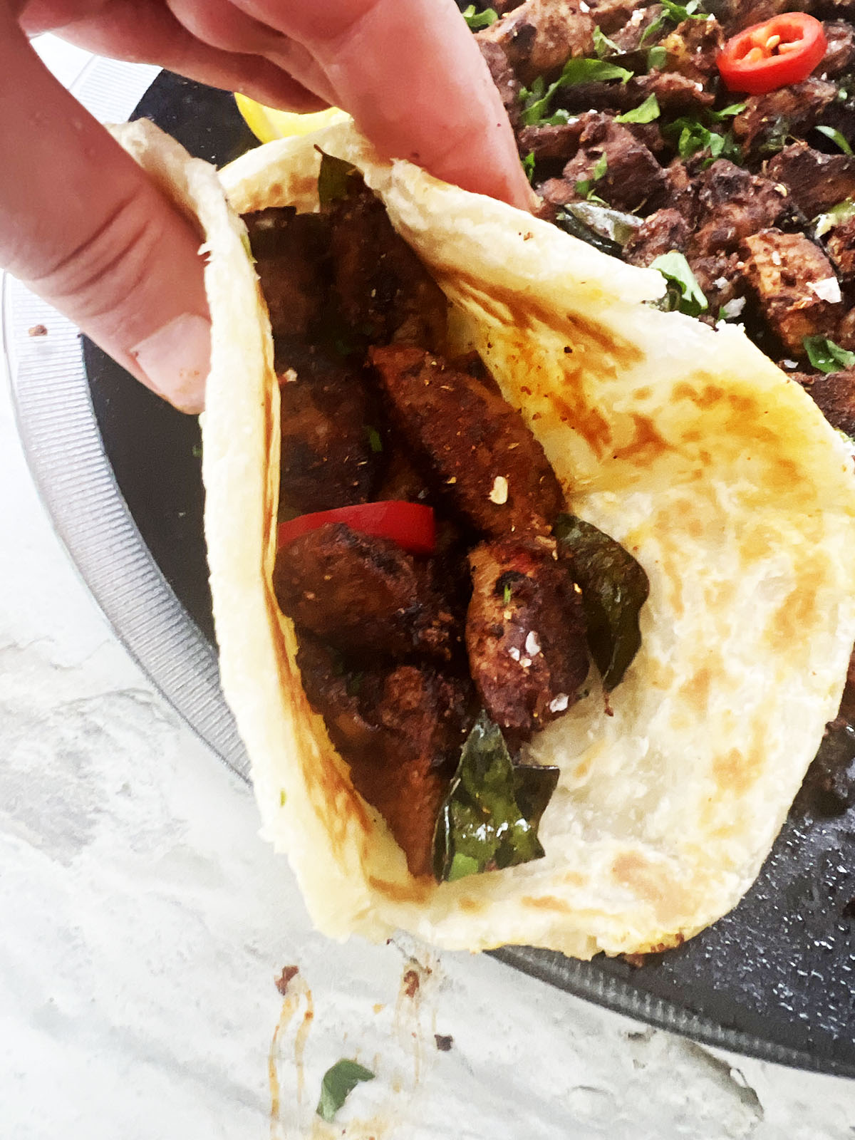 Lamb stir fry wrapped in a chapatti with cooked lamb in background