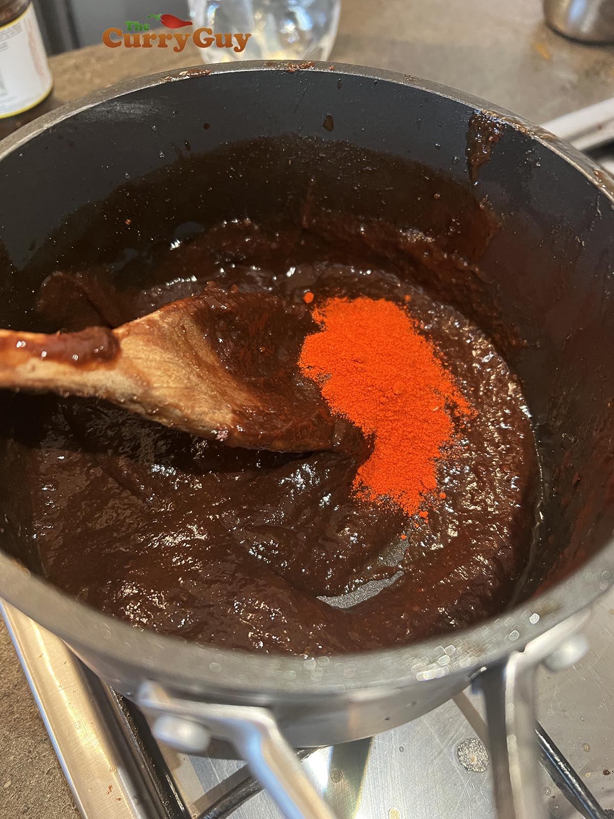 Adding chilli powder to tamarind concentrate.