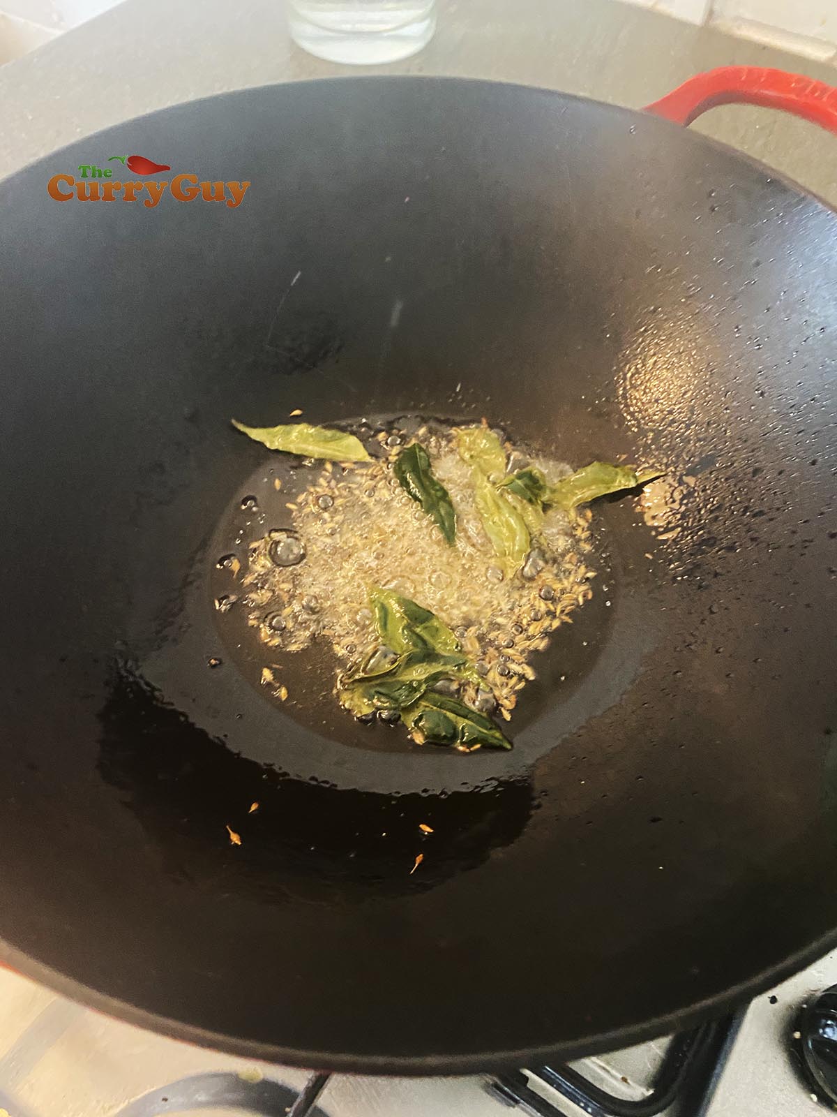Stirring in cumin seeds and curry leaves