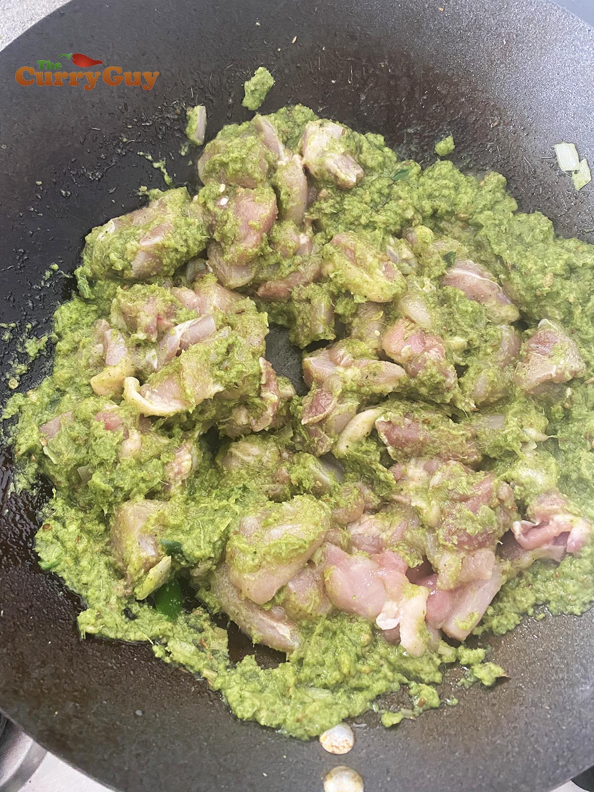 Stirring chicken into the green curry sauce