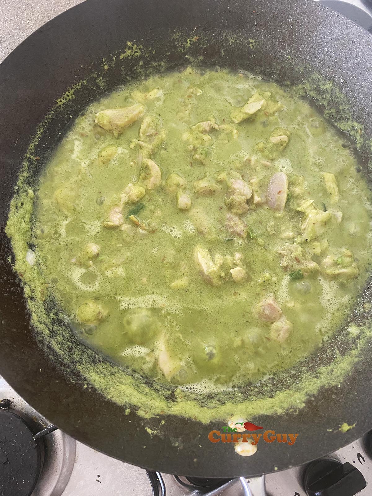 Adding stock to green curry sauce and chicken