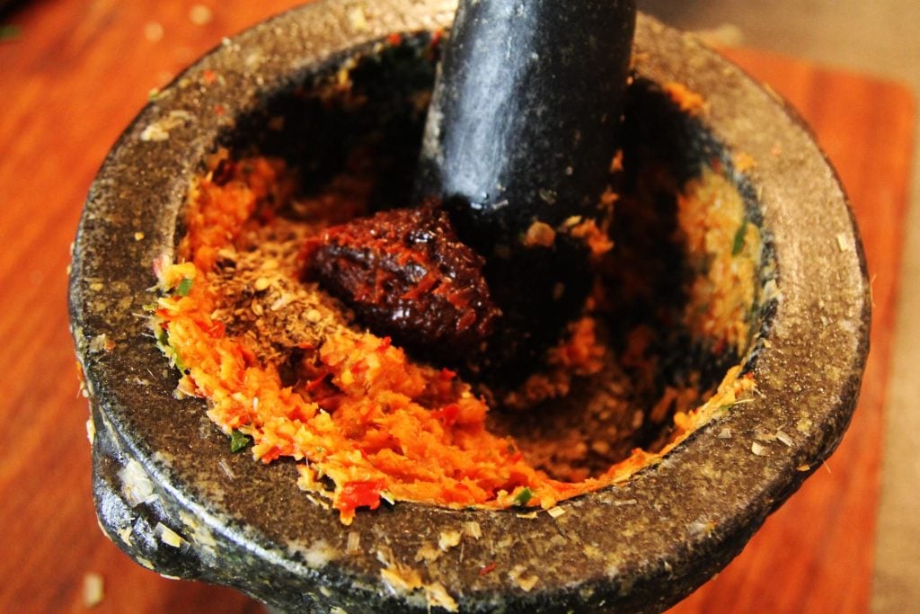 Adding shrimp paste to the other massaman curry paste ingredients.
