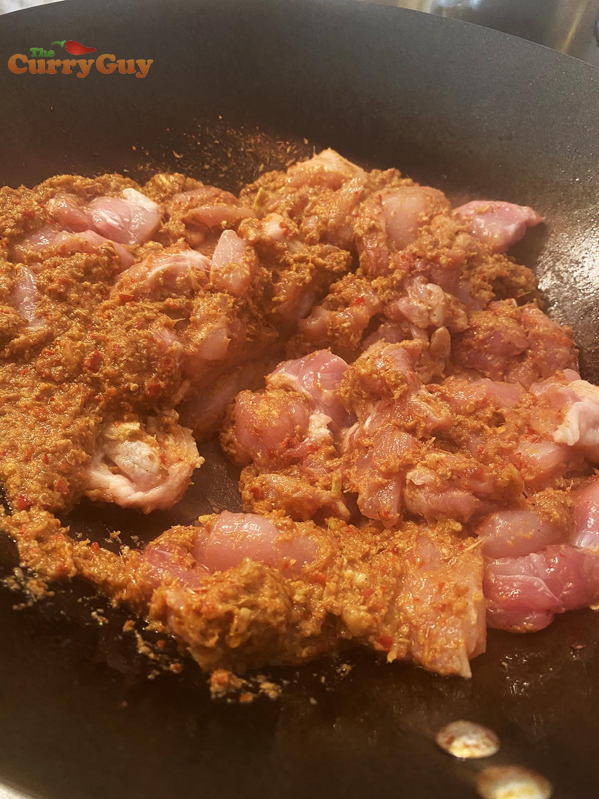 Stirring chicken into the curry paste