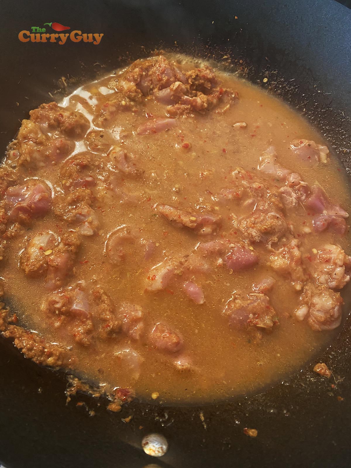 Adding chicken stock to the wok.