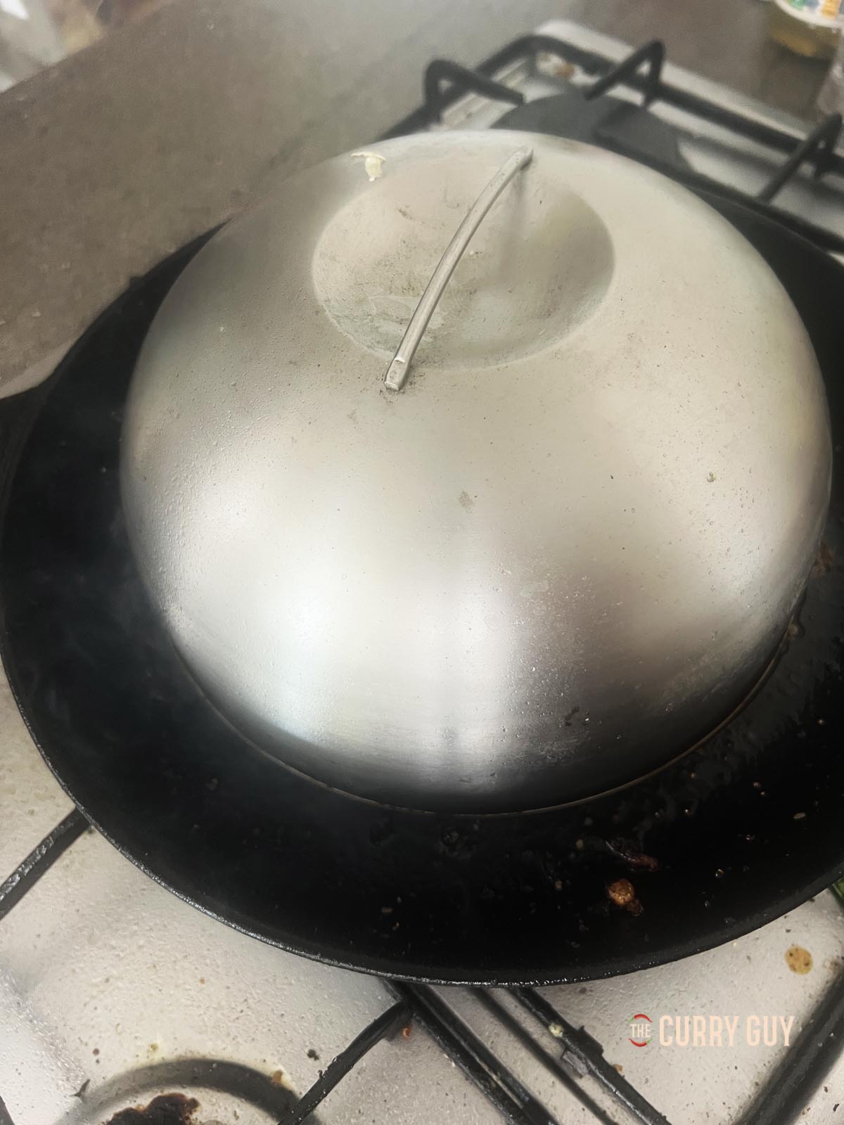 Topping the patties with a burger dome to help melt the cheese.