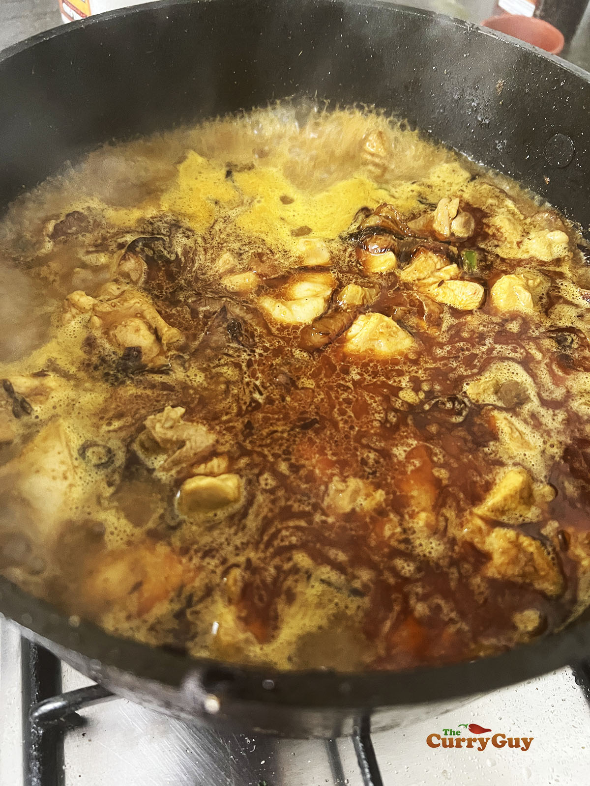 Simmering the chicken, onions and spices in the pan.