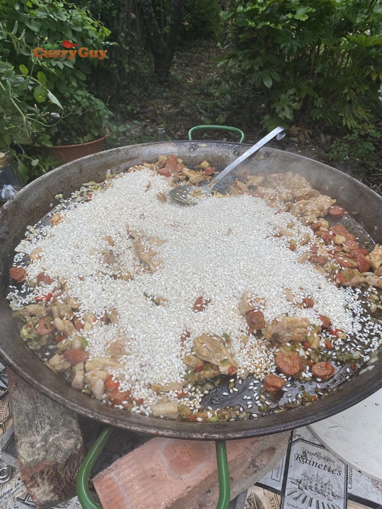 Adding rice to paella