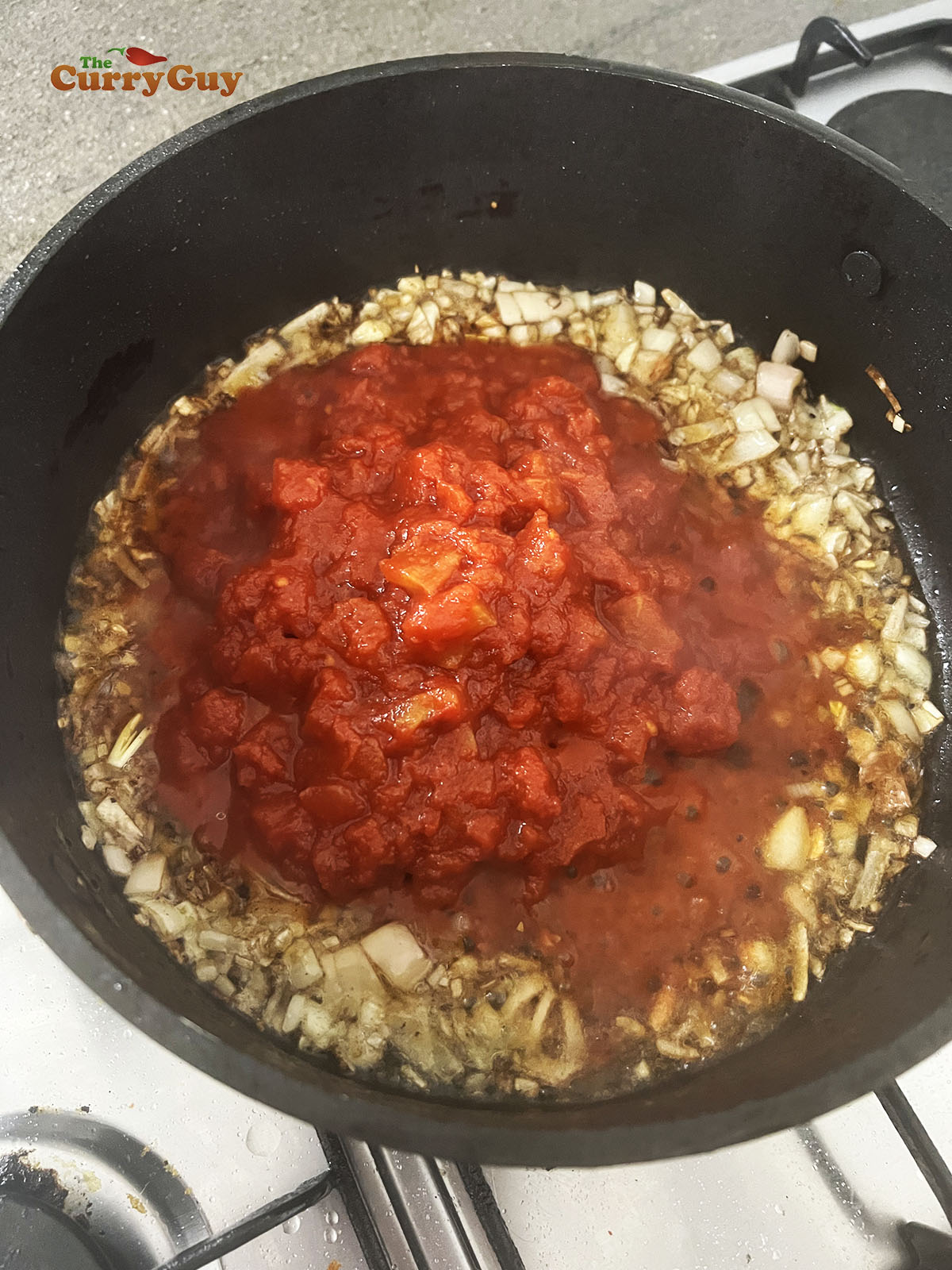 Adding chopped tomatoes to the pan.