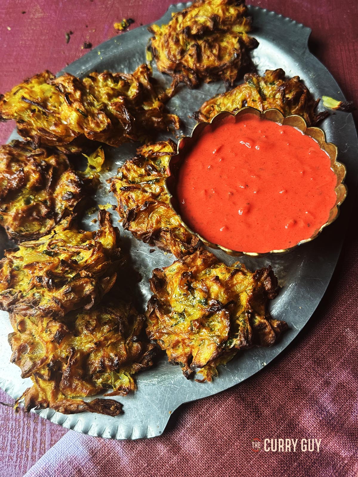 Air fryer onion bhajis on a serving platter with pakora dip.