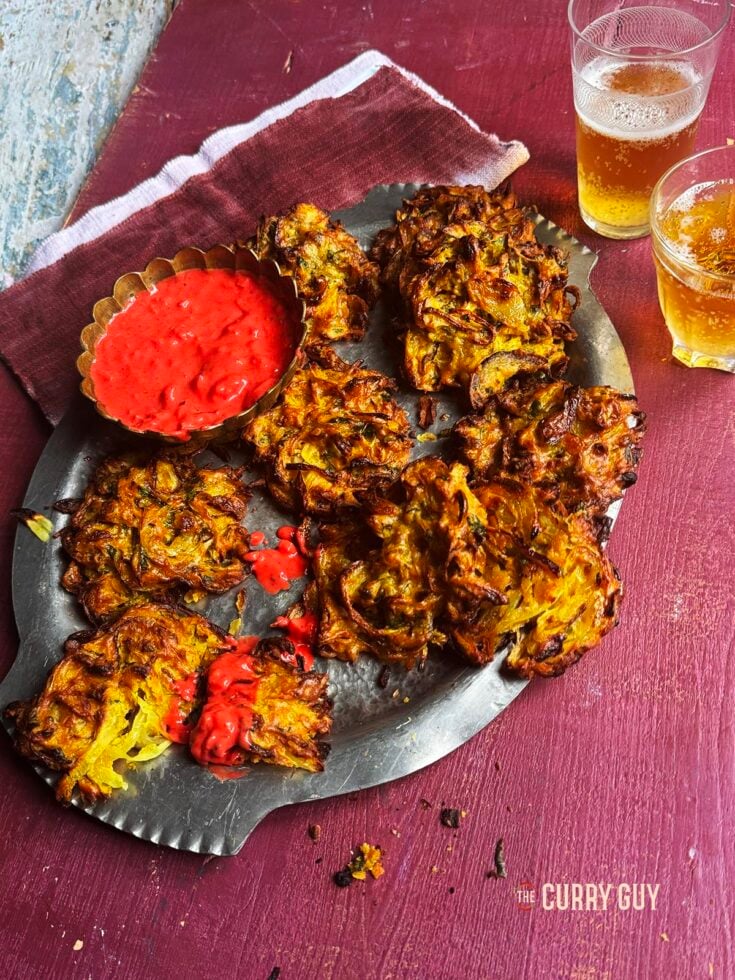Air fryer onion bhajis on a serving platter with pakora dip.