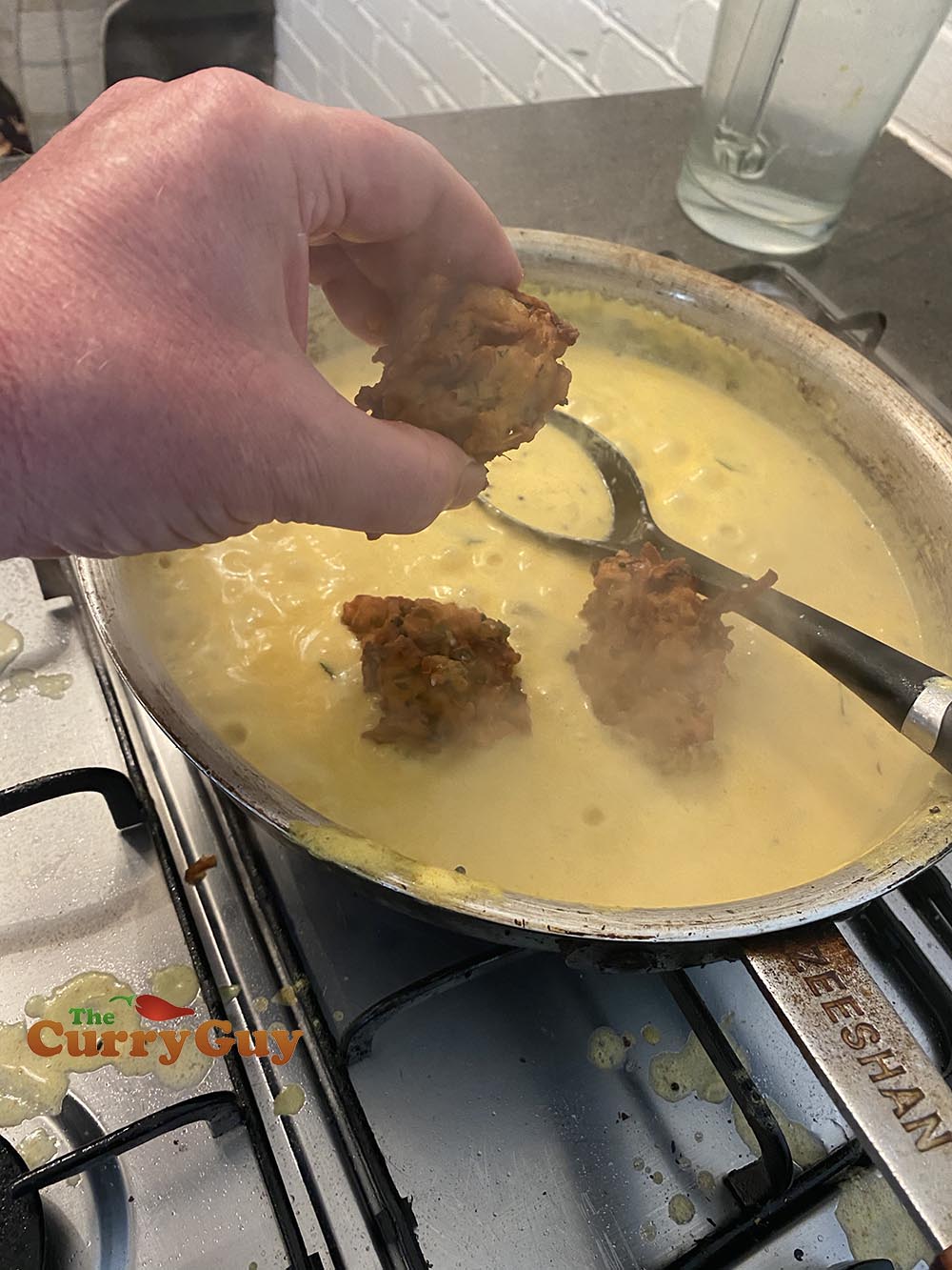 Adding the onion bhajis to the onion bhaji curry