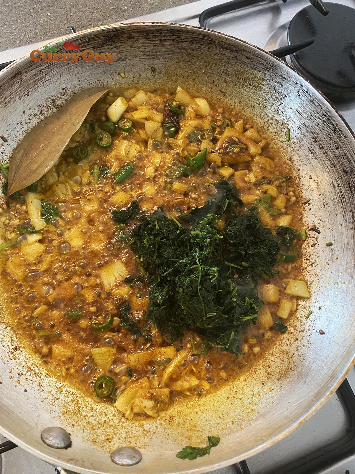 Adding methi to curry.