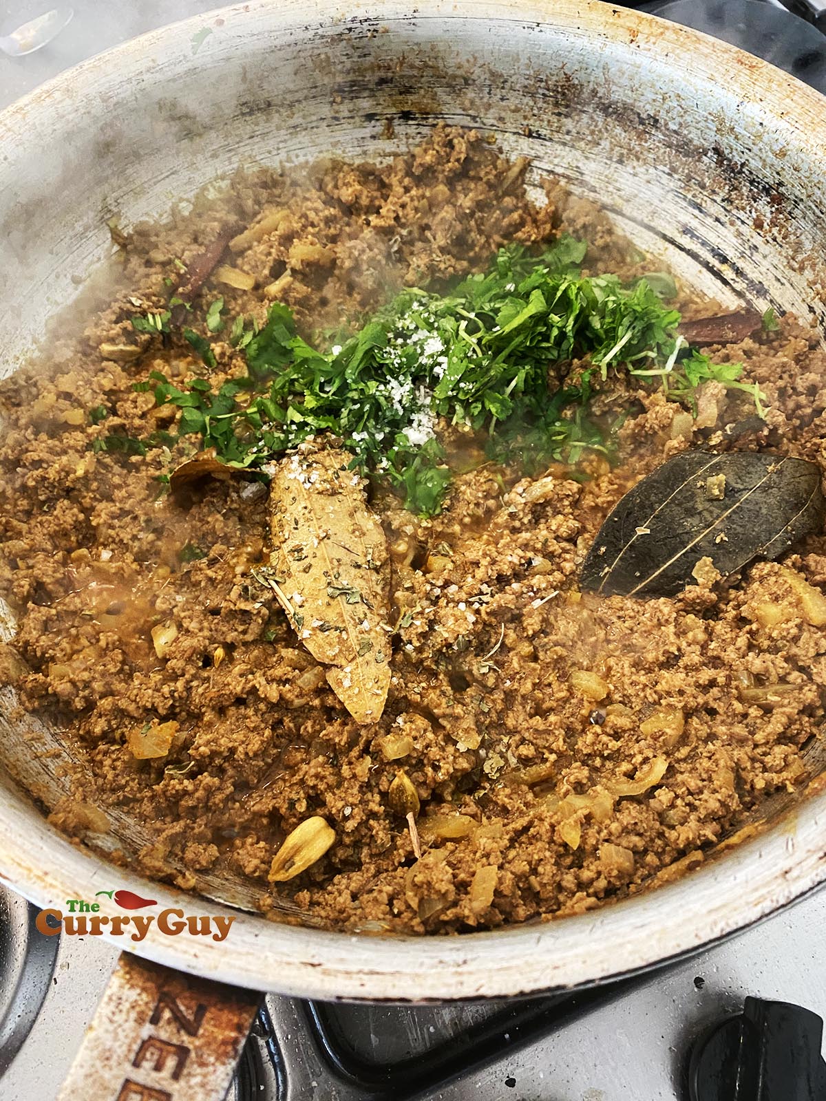 Adding coriander (cilantro) and kasoori methi to the pan.